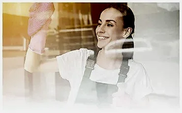 Uśmiechnięta kobieta myjąca okno